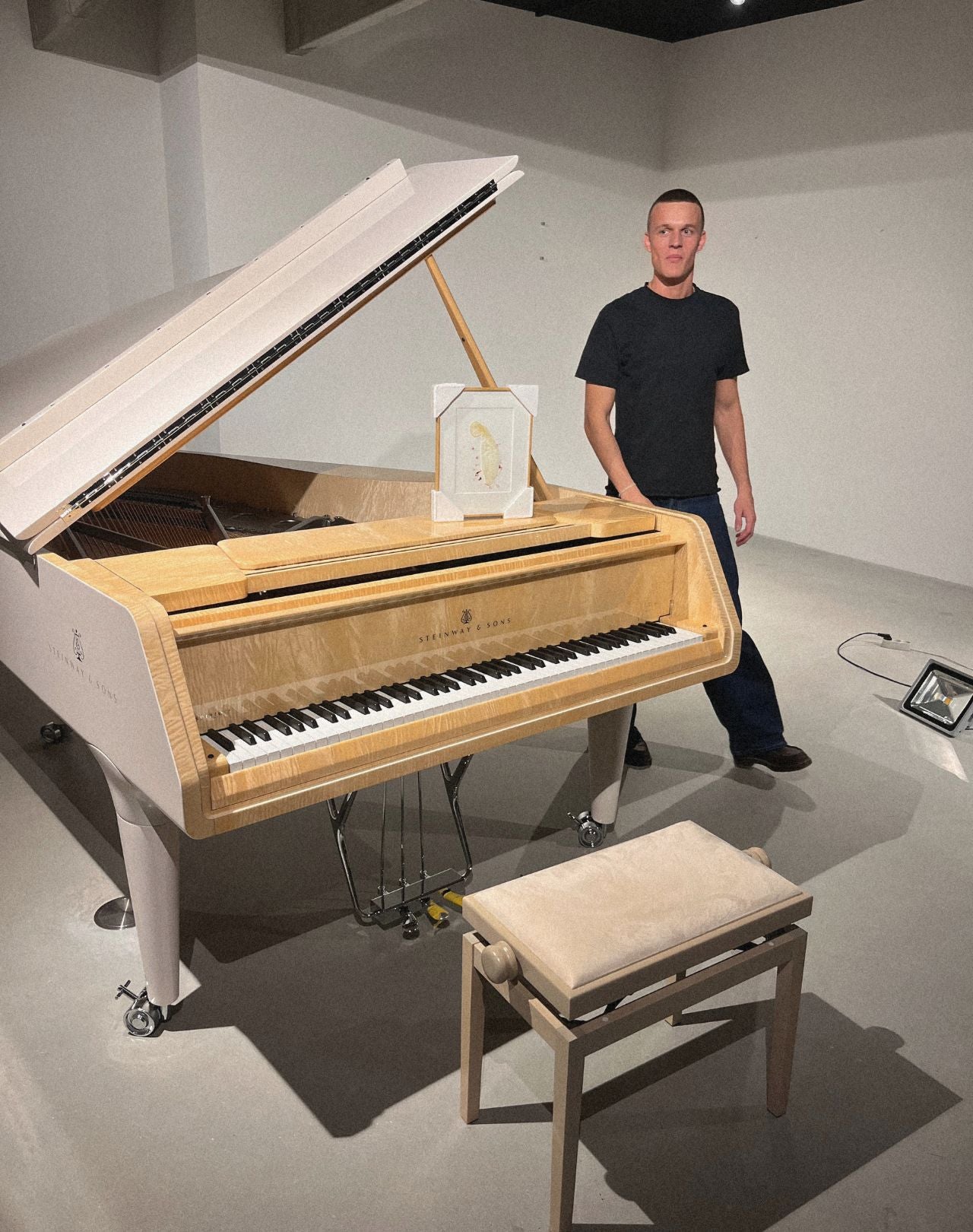 Thomas Hanscomb next to his artwork displayed on a piano